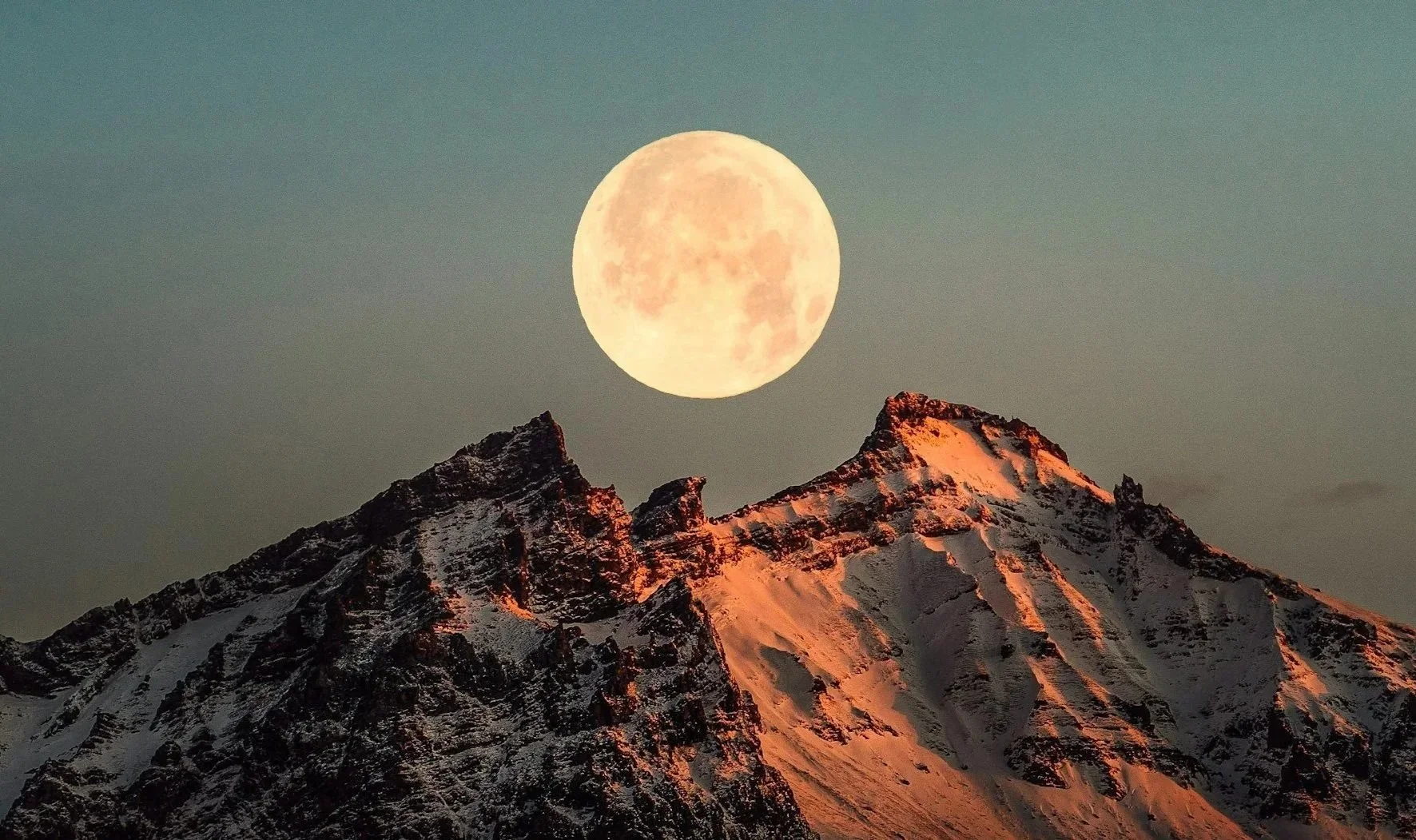 Aerin Frances Structural Bodywork and Signature Massages in London: A full moon rising over snow-capped mountain peaks at sunset, reflecting a serene and grounding clinical sanctuary.