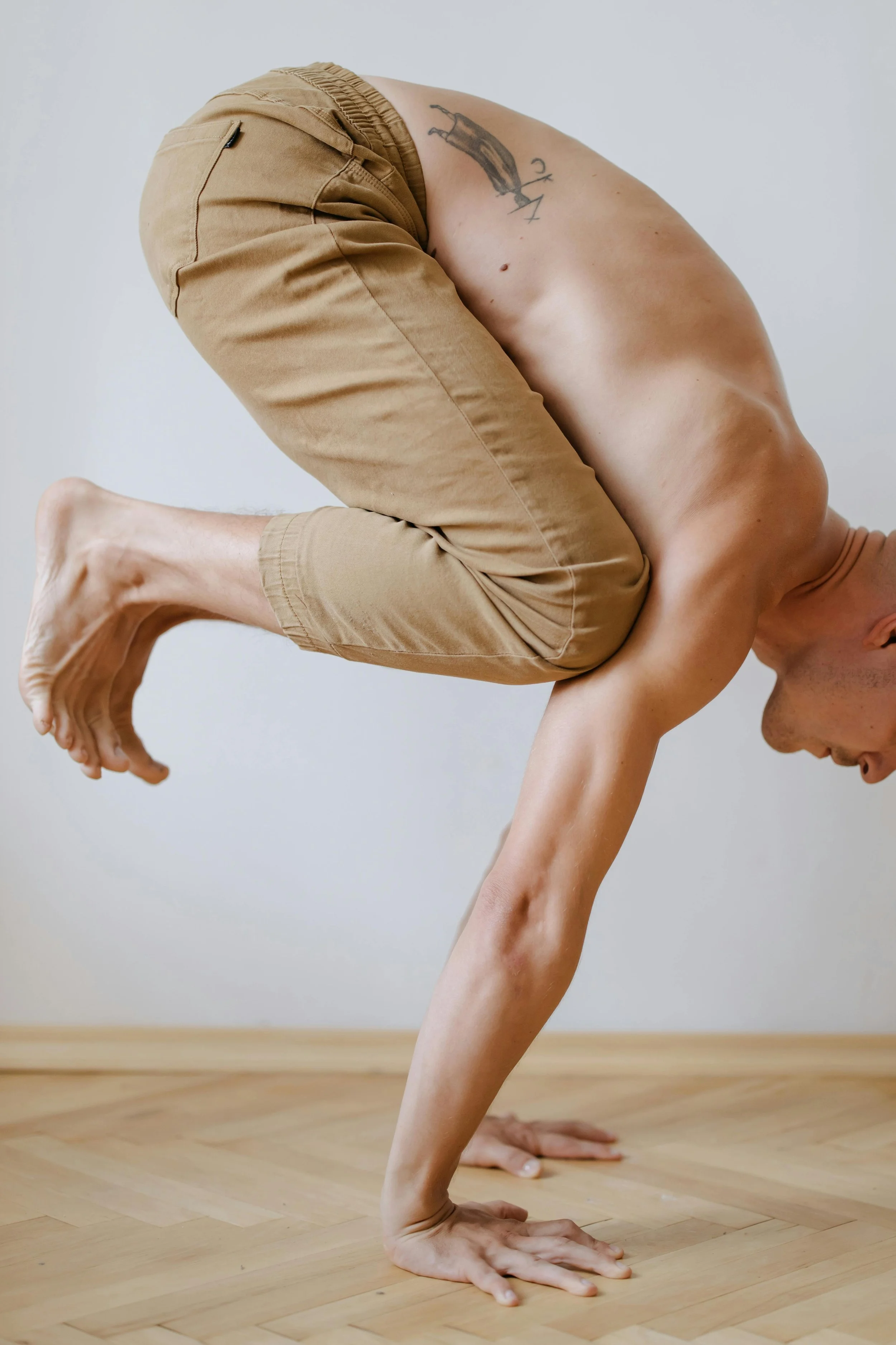 A man in crow pose, practicing in a Yoga Studio