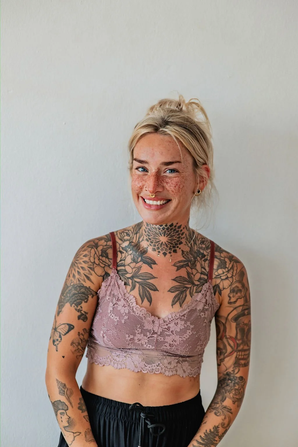 Jane with her hair up in a pink crop-top and black flair pants, smiling to the camera.
