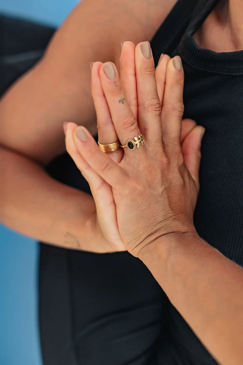 Close-up of female hands in prayer pose. Golden rings on each hand.