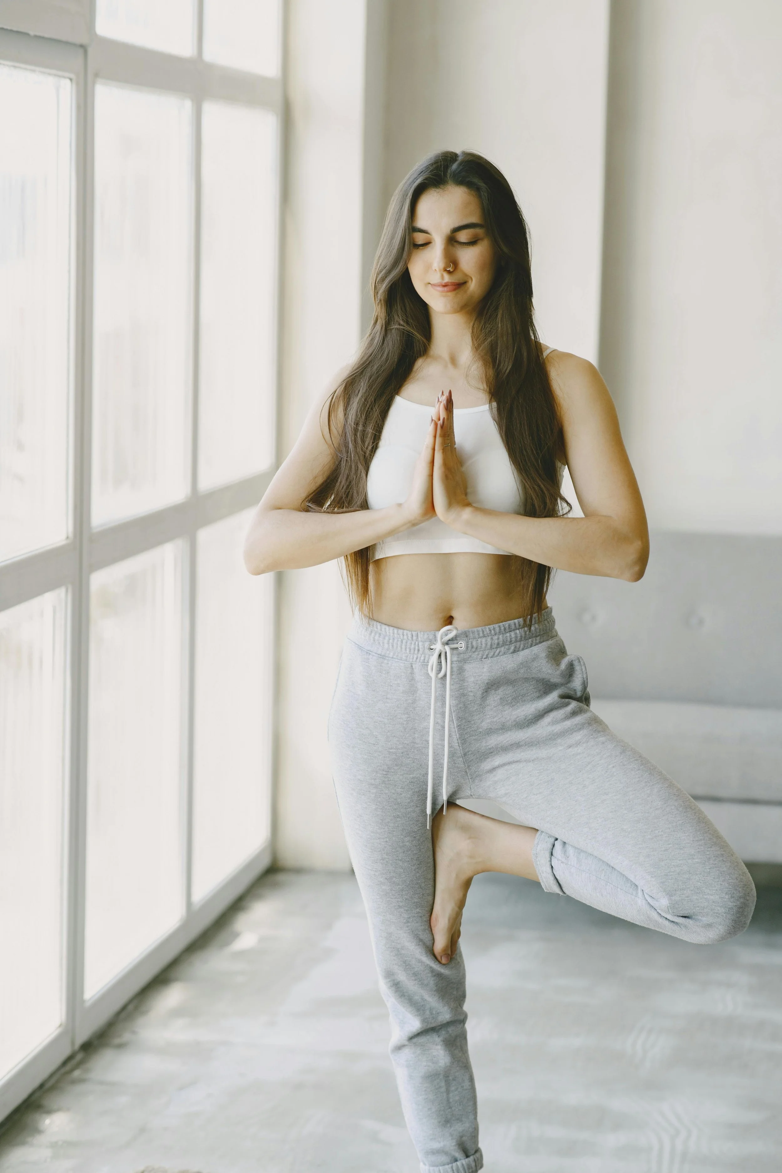 Woman performing the tree pose in a light room