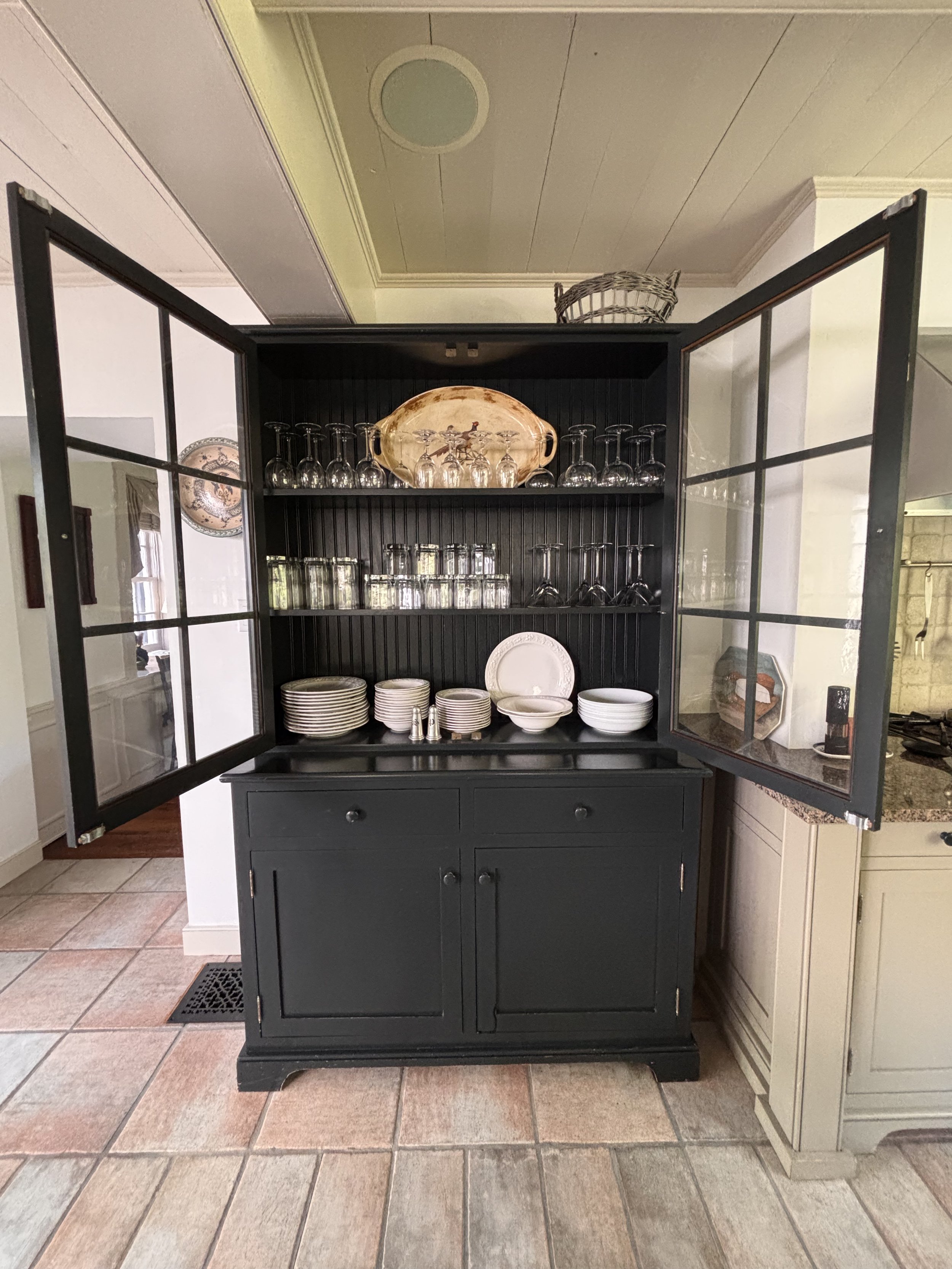 Fully stocked china cabinet with wine glasses, rocks tumblers, and complete set of dishes and antique silverware