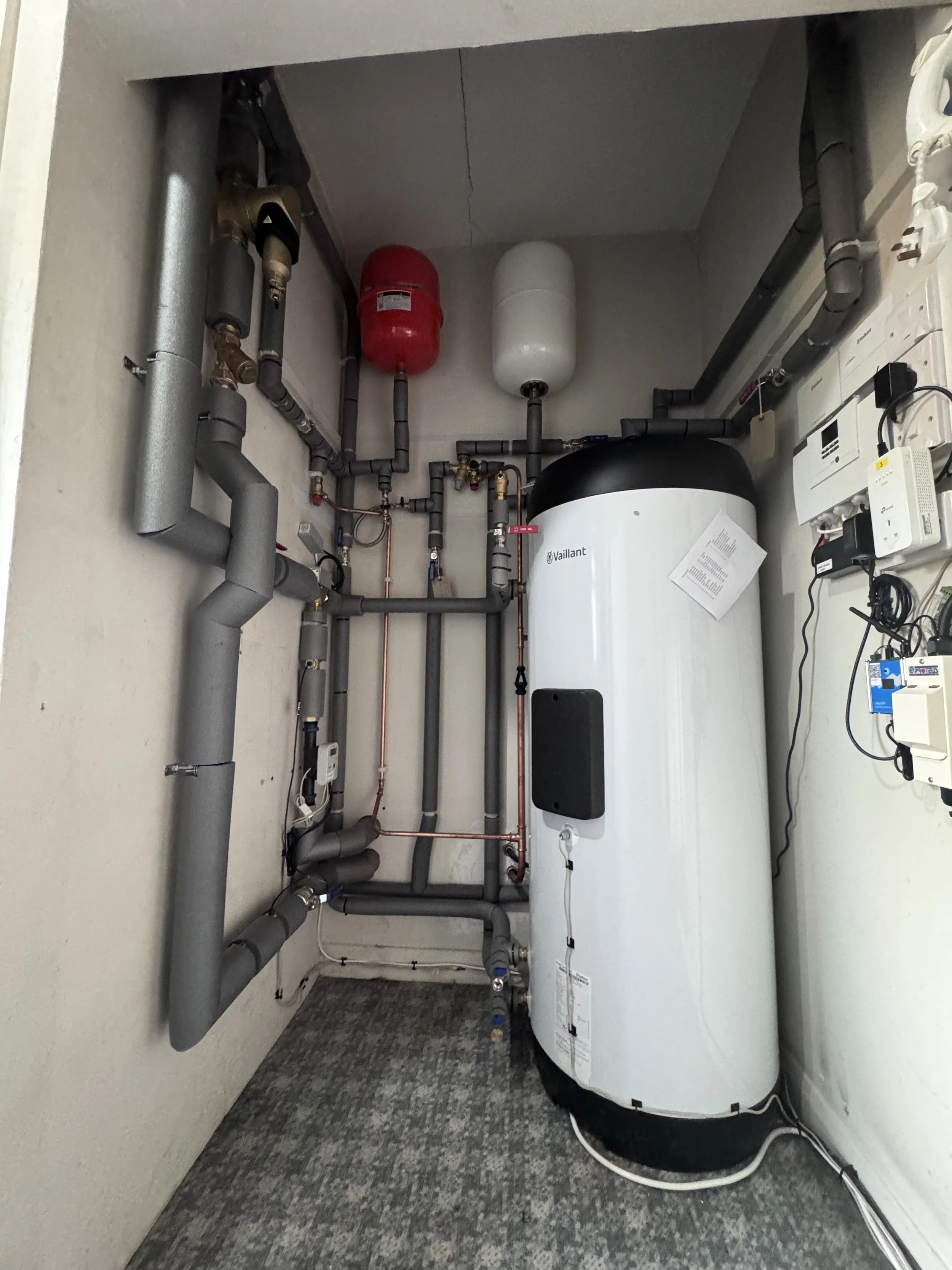 A vaillant arotherm plus plant room with a vaillant hot water cylinder and an open energy monitor.