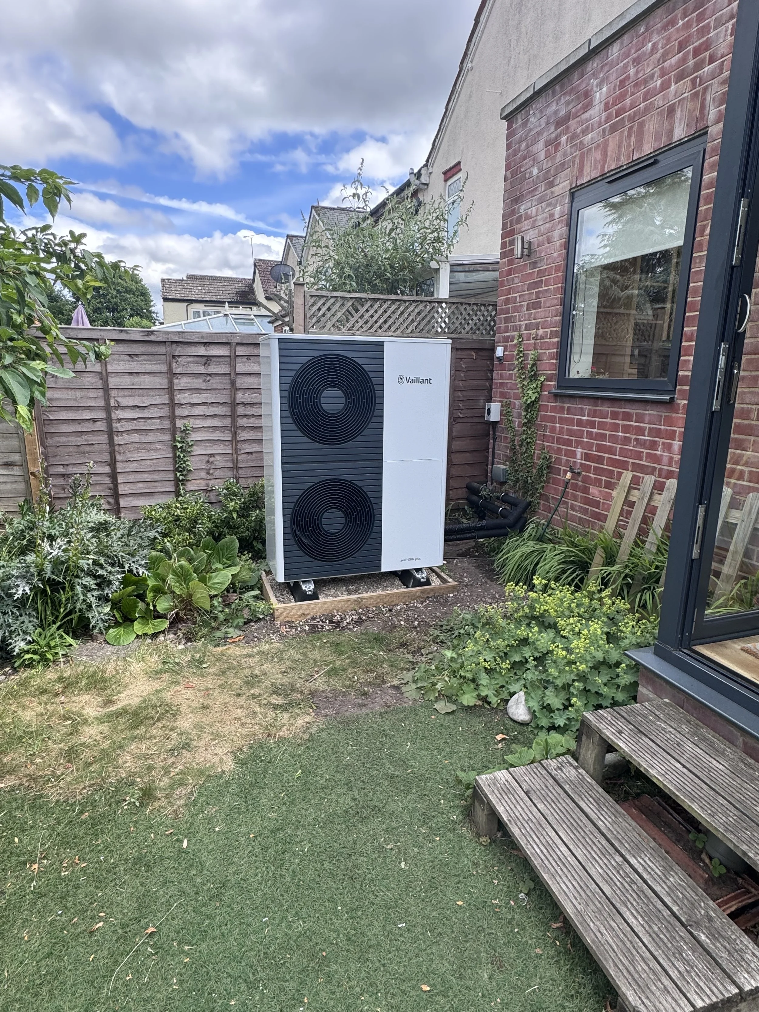 a garden photo with a vaillant arotherm plus heat pump fitted on an appropriate base