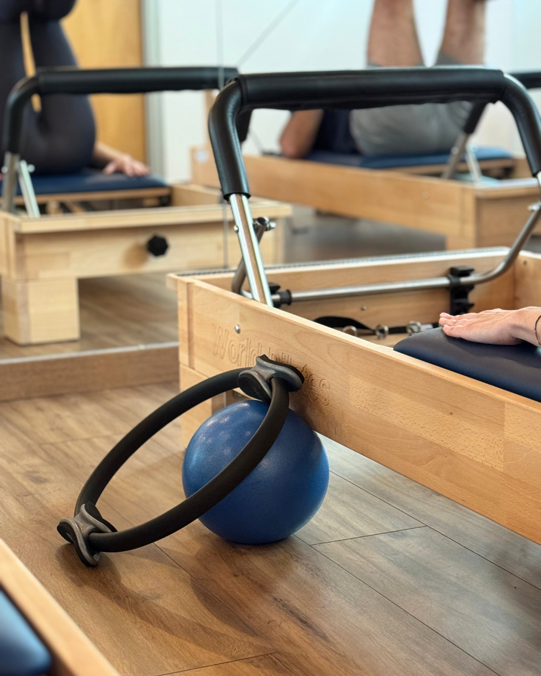 Attrezzi di Pilates: palla blu, cerchio di pilates nero, e reformer in uno studio di Pilates.