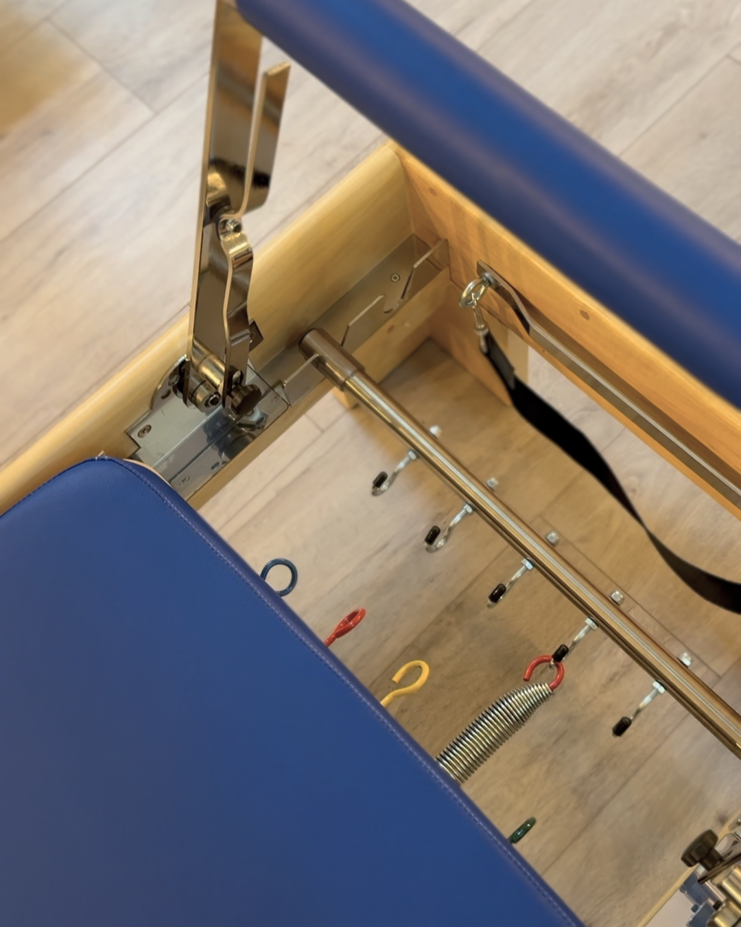 Particolare di un reformer, sedile imbottito blu e footbar.