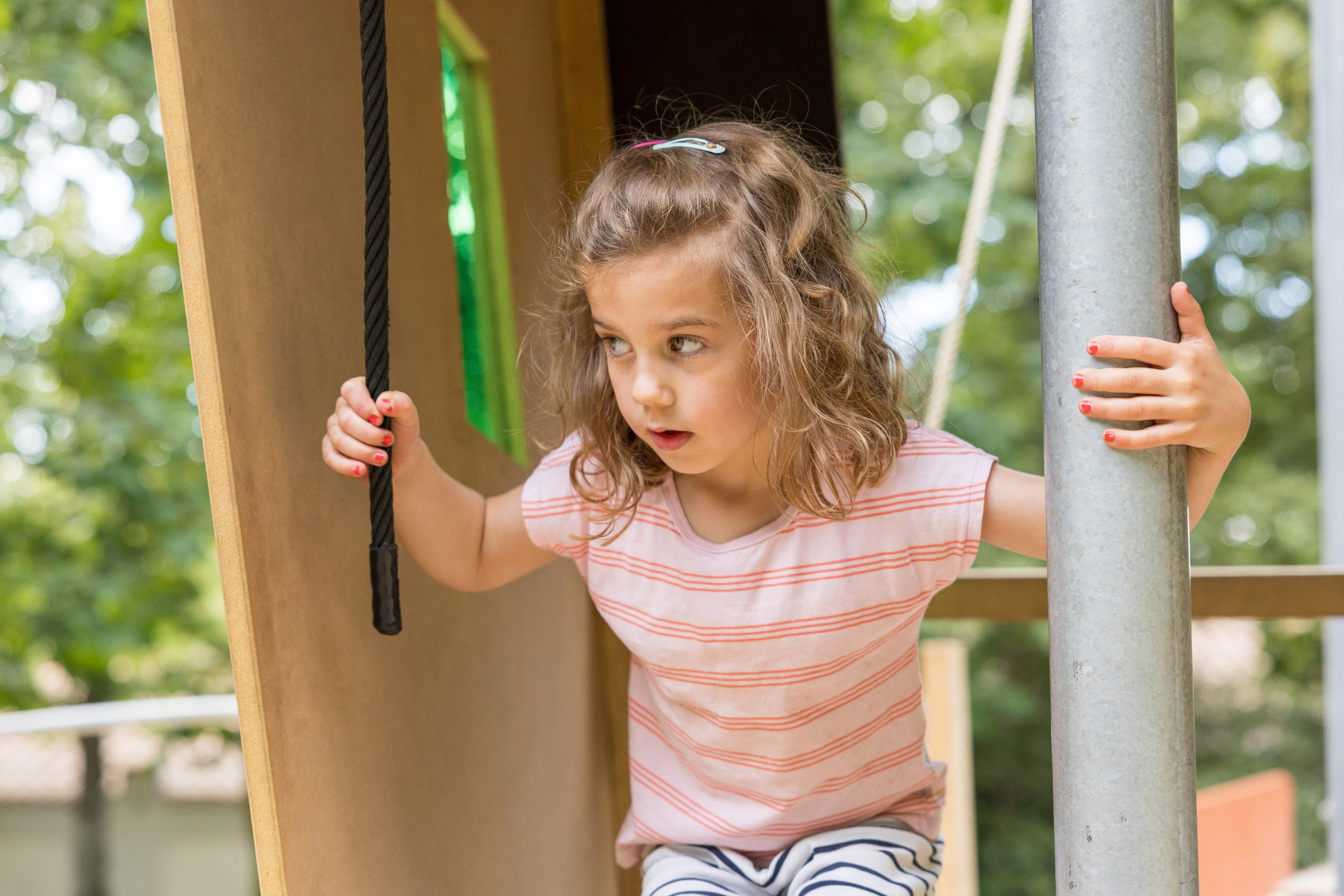 Mädchen beim Klettern auf einem Spielplatz – ungestellte Kinderfotografie in Bewegung.