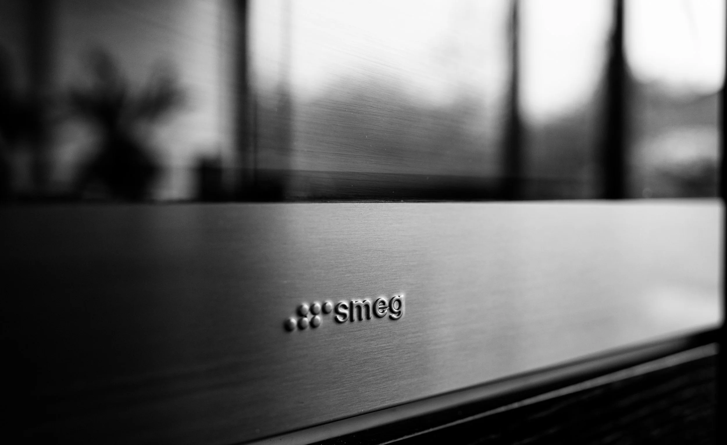 Close-up of a stainless steel smeg appliance with its logo visible on the front.