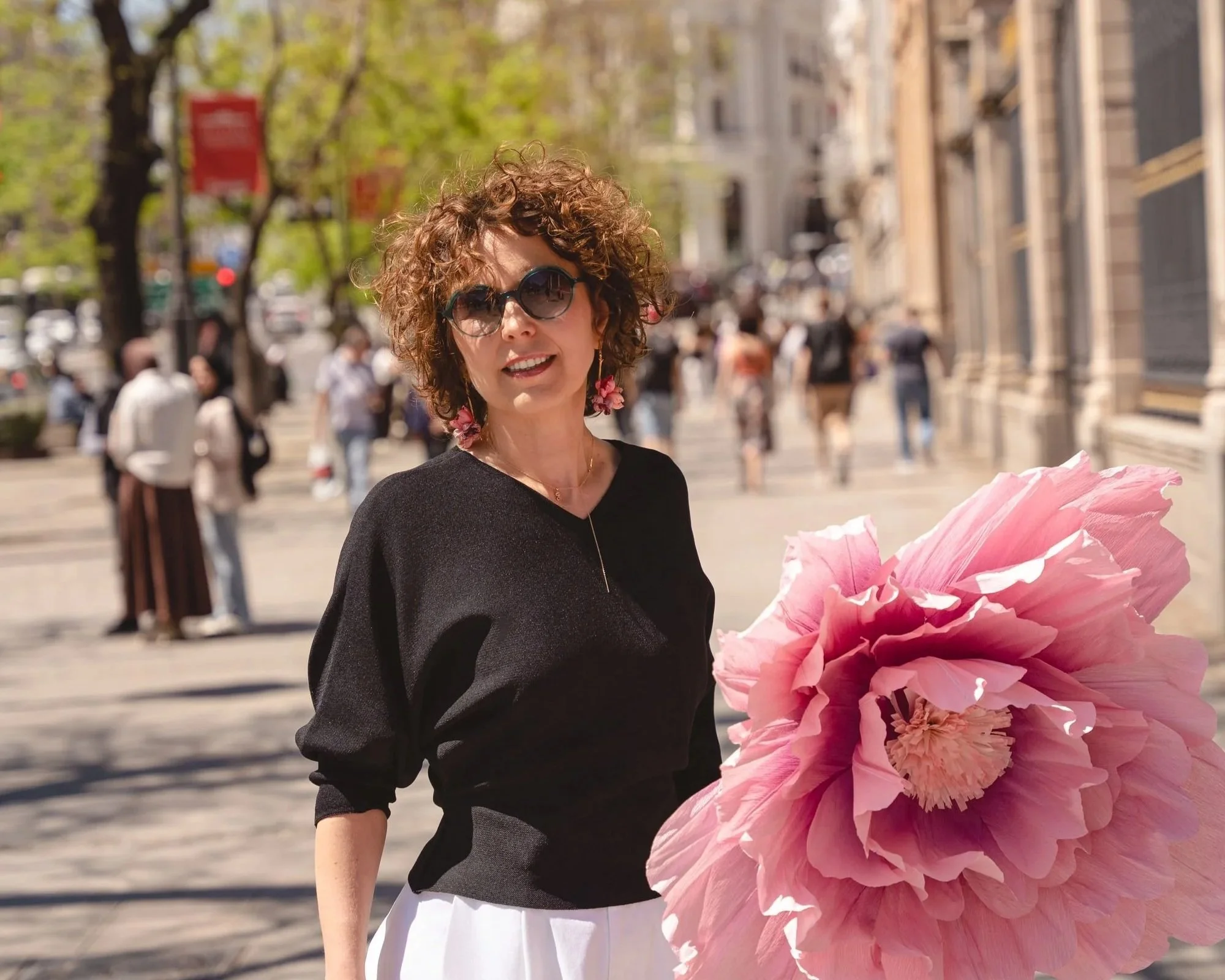 Coach Peony Path Coaching spacerująca po Gran Via w Madrycie z dużym różowym kwiatem