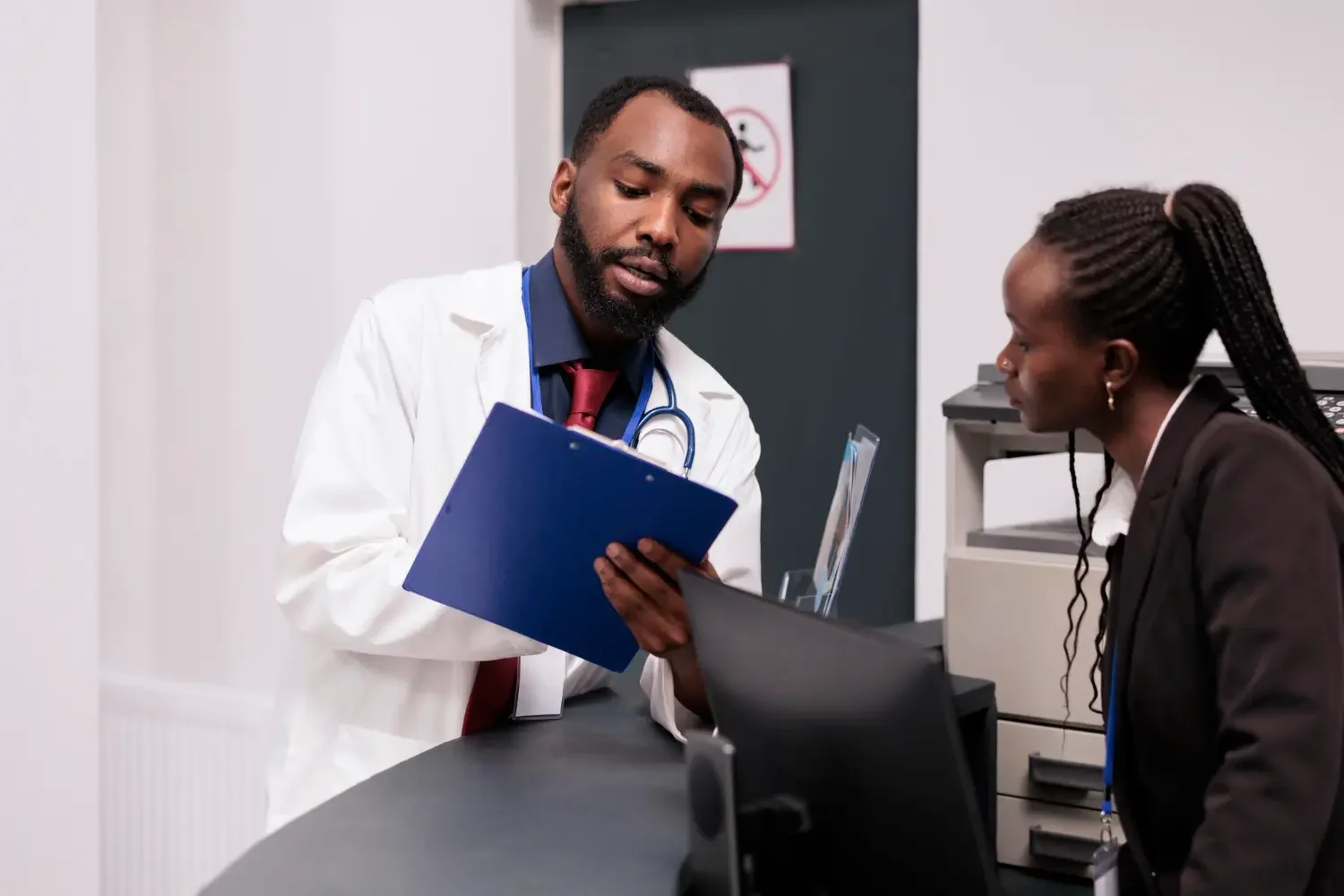 A doctor shows documents to a woman patient in a medical office.