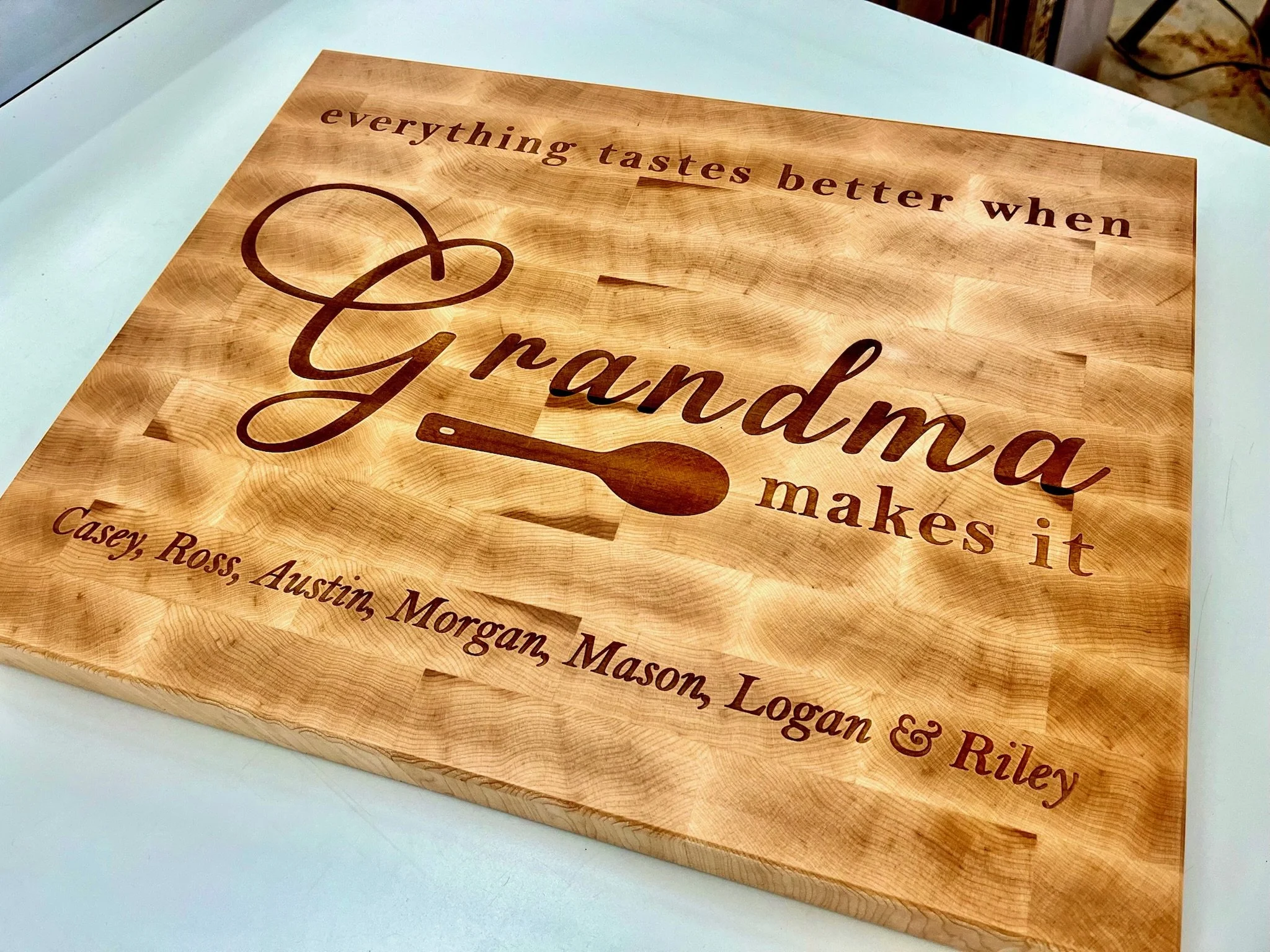 A wooden cutting board with a quote engraved that reads, 'everything tastes better when &,' with a small chef's knife icon and additional text partially visible below.
