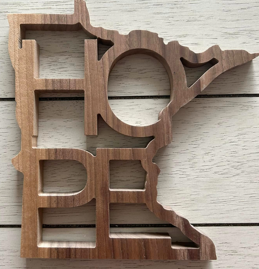 A wooden cutout with the word "LOVE" in capital letters, with the letter "O" shaped like a heart, and the right side features an outline of the state of Texas.
