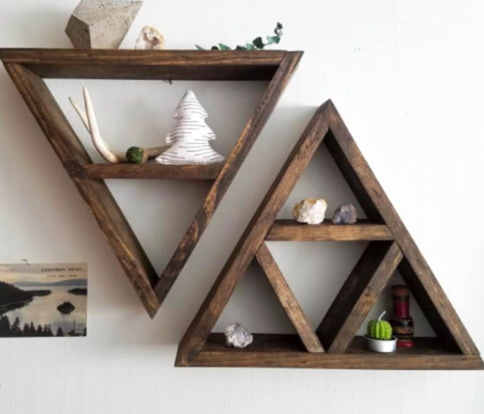 Decorative wooden geometric wall shelves with various rocks and decorative objects, mounted on a white wall, with a photo of a natural landscape partially visible below.