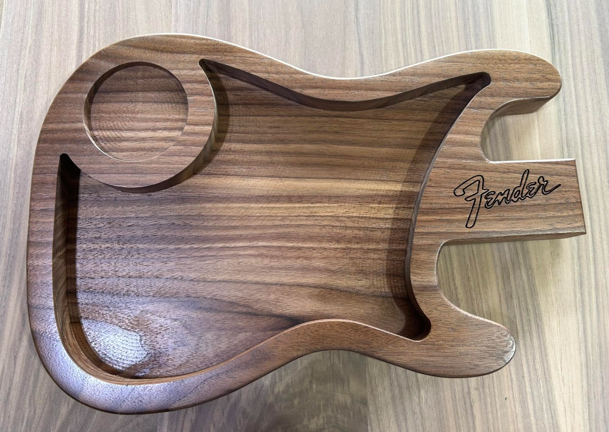 A wooden decorative piece in the shape of a guitar, with the word "Fender" engraved on it.