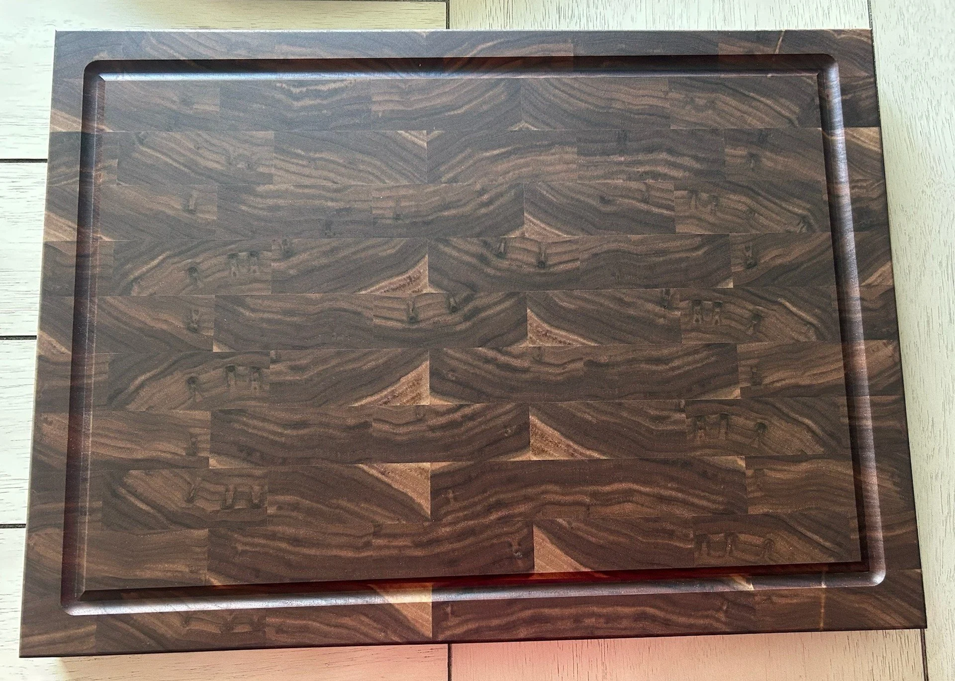 A dark wooden chessboard with a glossy finish on a light wooden surface, with a visible wood grain pattern.