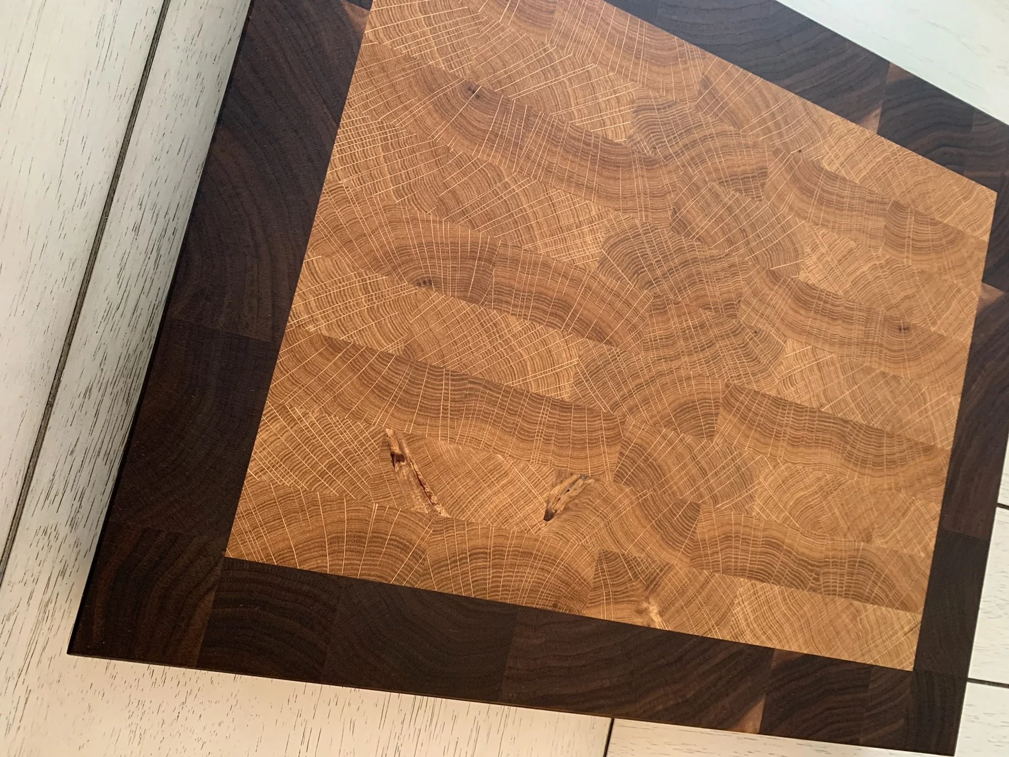 Close-up of a decorative wooden art piece with a geometric pattern, placed on a white speckled surface.