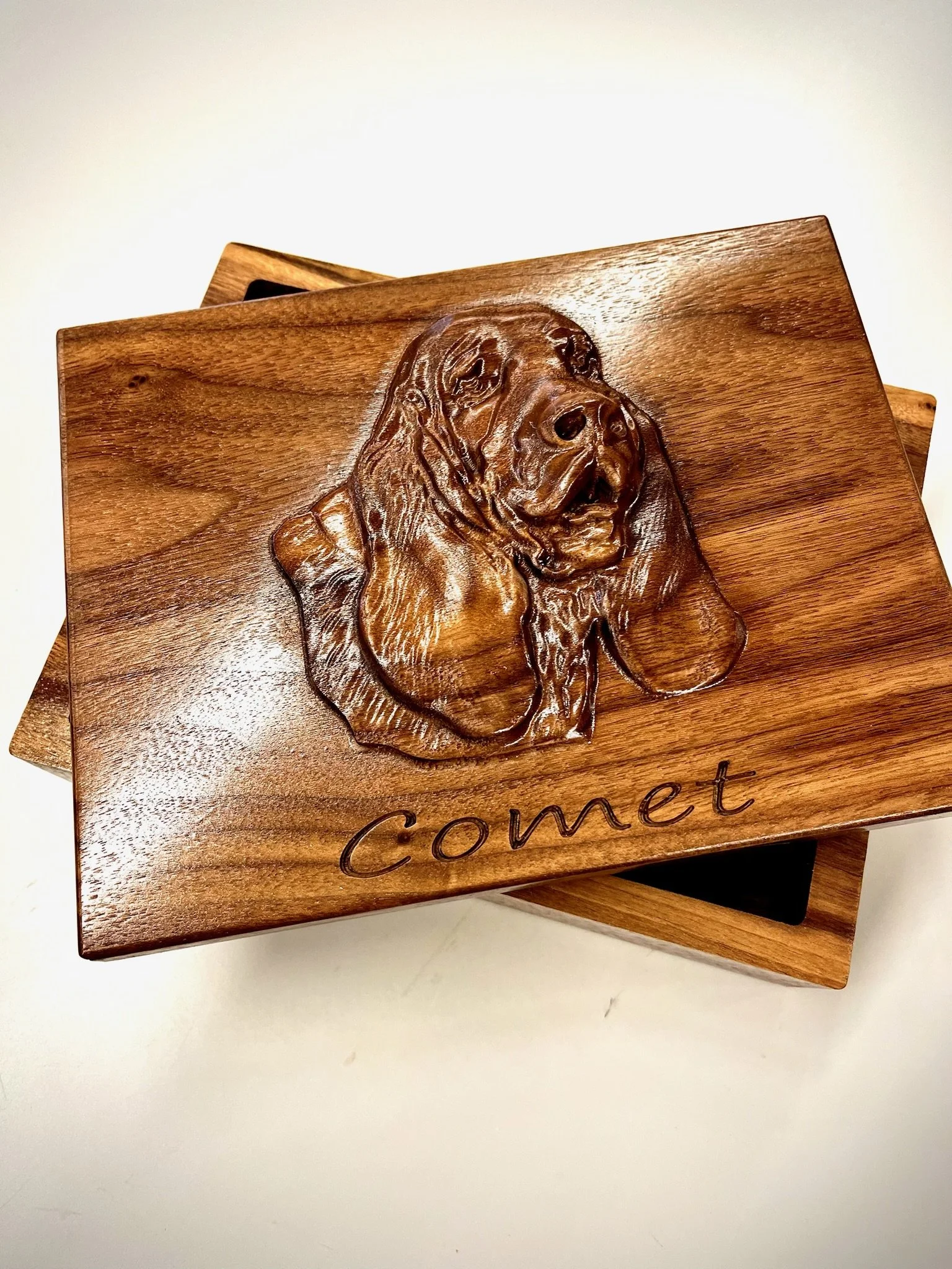 Close-up of a wooden plaque with a carved image of a dog and the word "Comet" engraved on it.