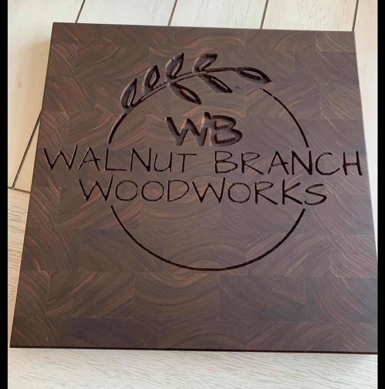 Wooden sign with engraved circular logo reading 'Walnut Branch Woodworks' and initials 'W3' with a decorative branch design.