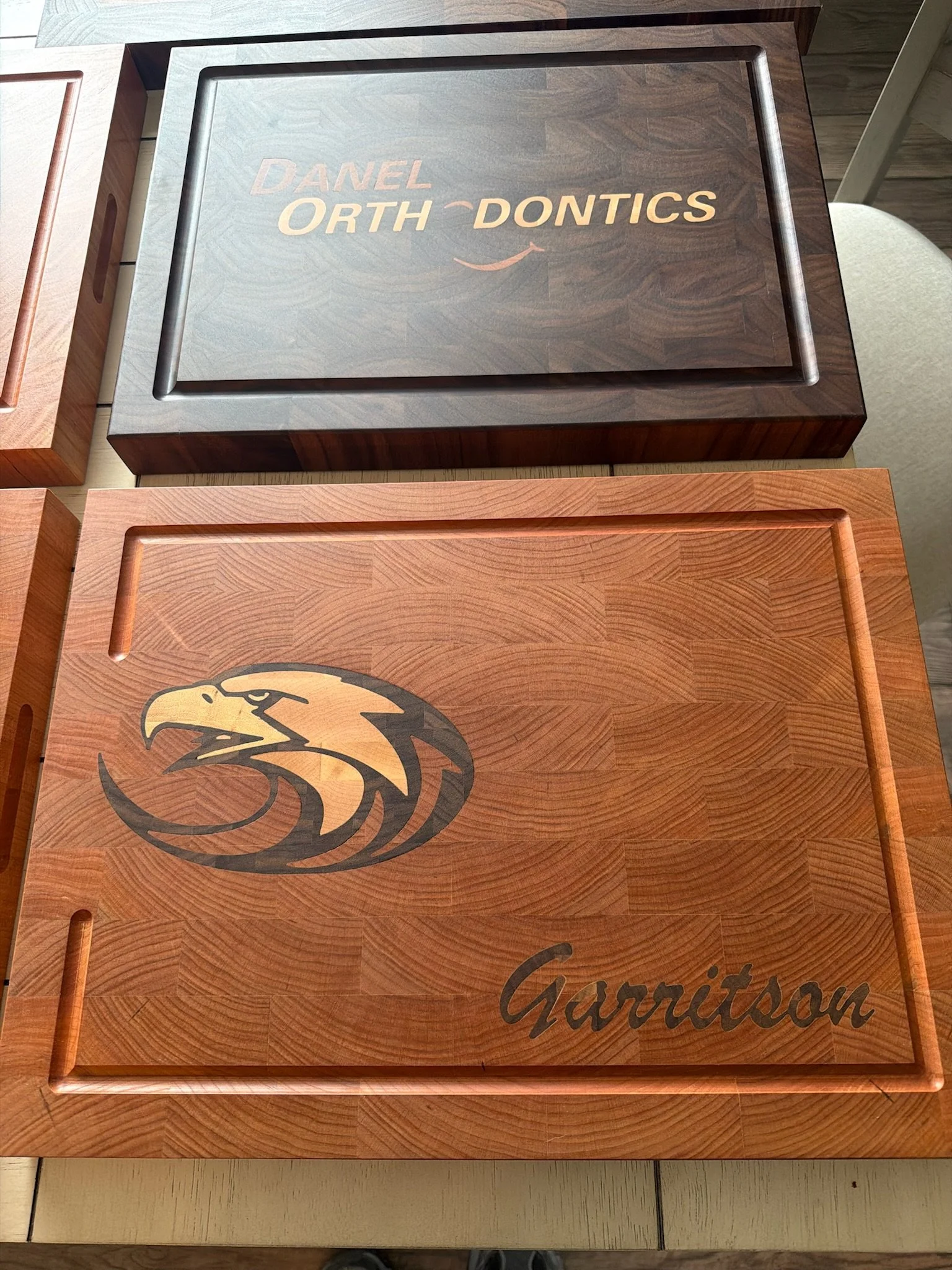 Wooden box with the words 'DANEL ORTH DONTICS' engraved on the lid, and a logo of an eagle's head in black and gold. The box is on display among other similar boxes.