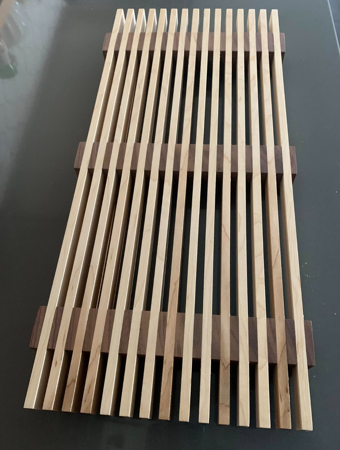 Wooden slatted rack with dark brown supports on a black surface.