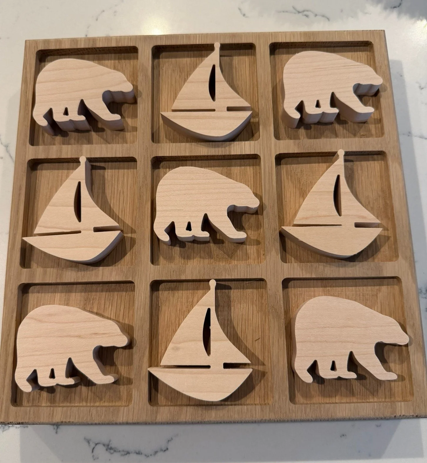 Wooden puzzle with cutouts of bears and sailboats on a wooden grid.