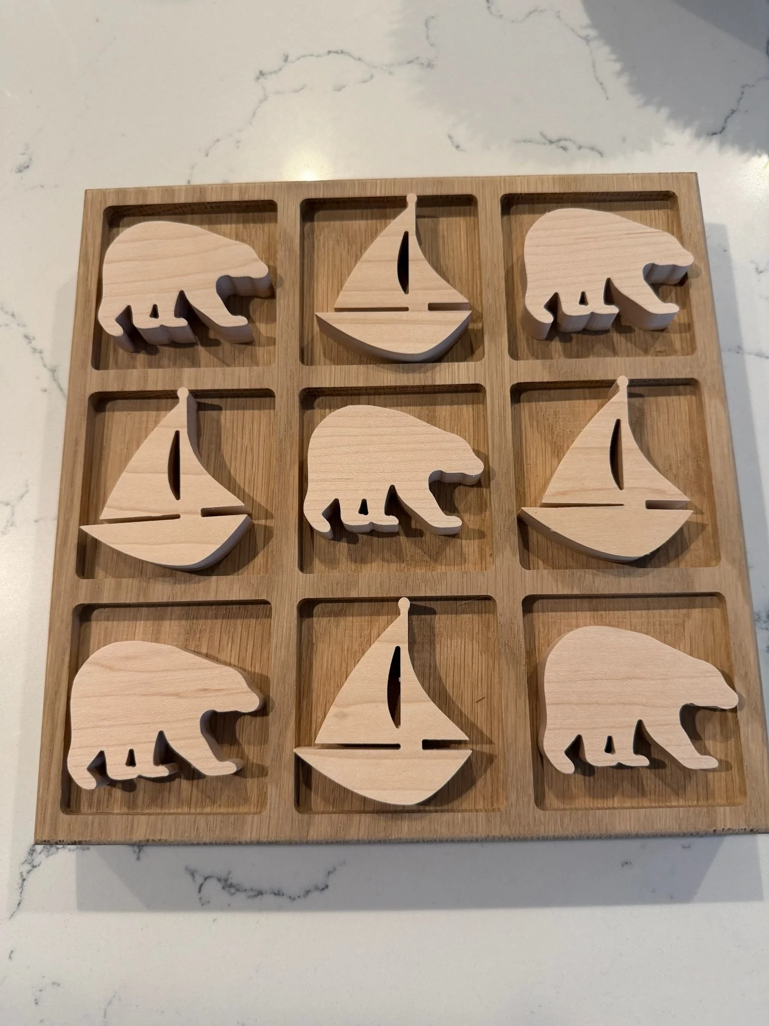 Wooden 3x3 grid with cutouts of bears and sailboats.