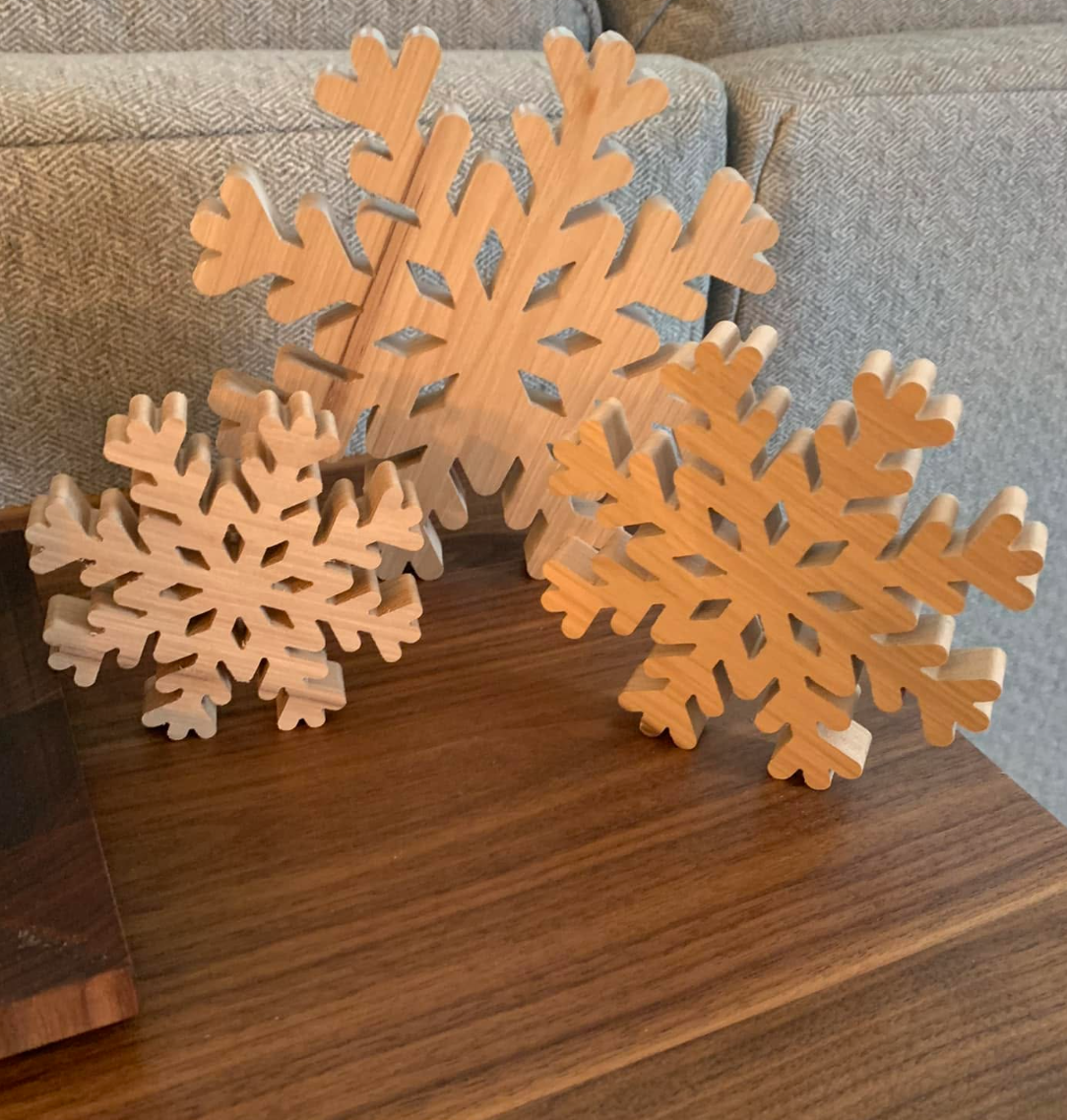 Three wooden snowflake decorations placed on a wooden surface near a gray couch.