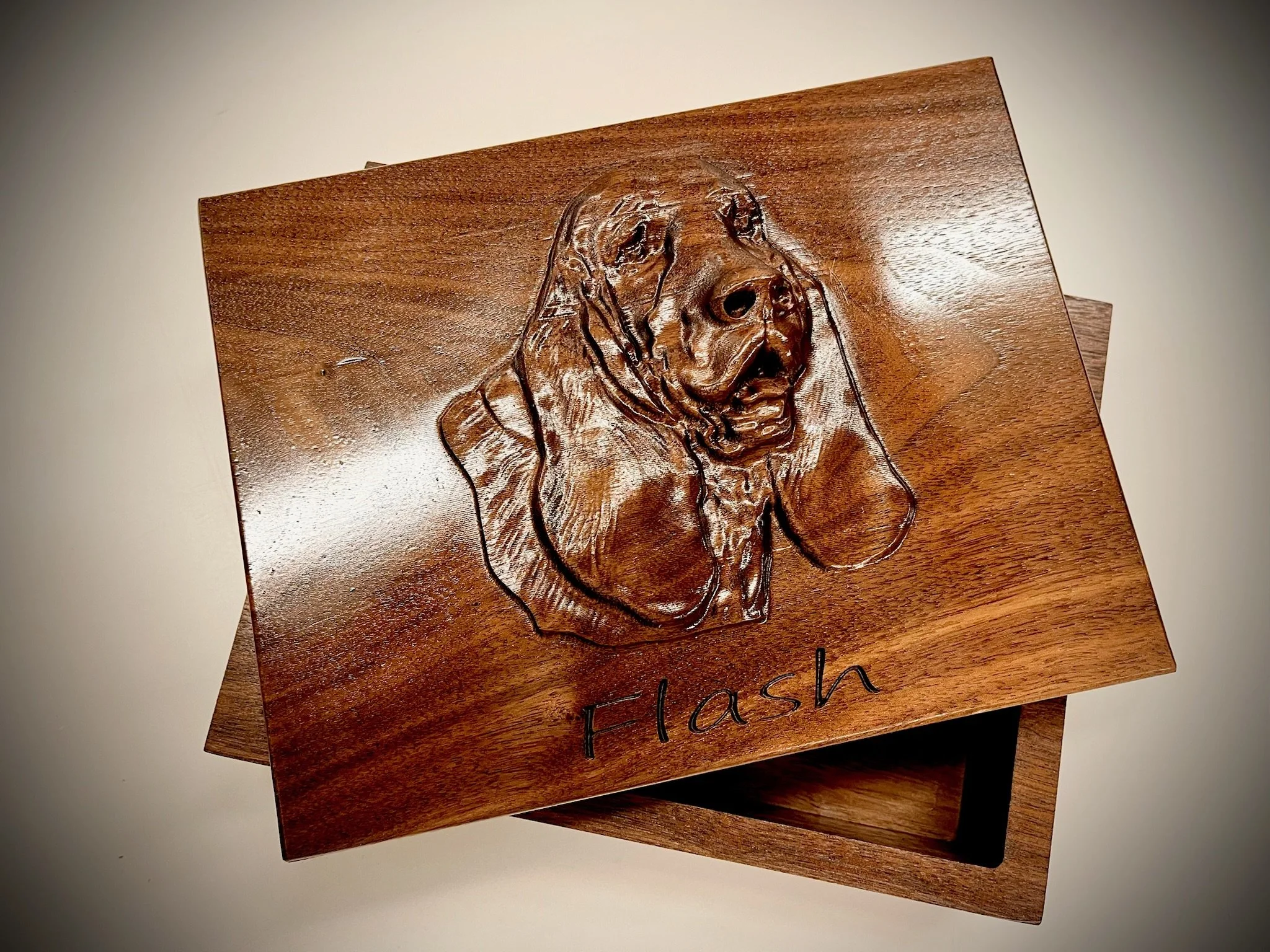 Wooden plaques with engraved dog portraits and the word "Flash" written on the bottom of one plaque.