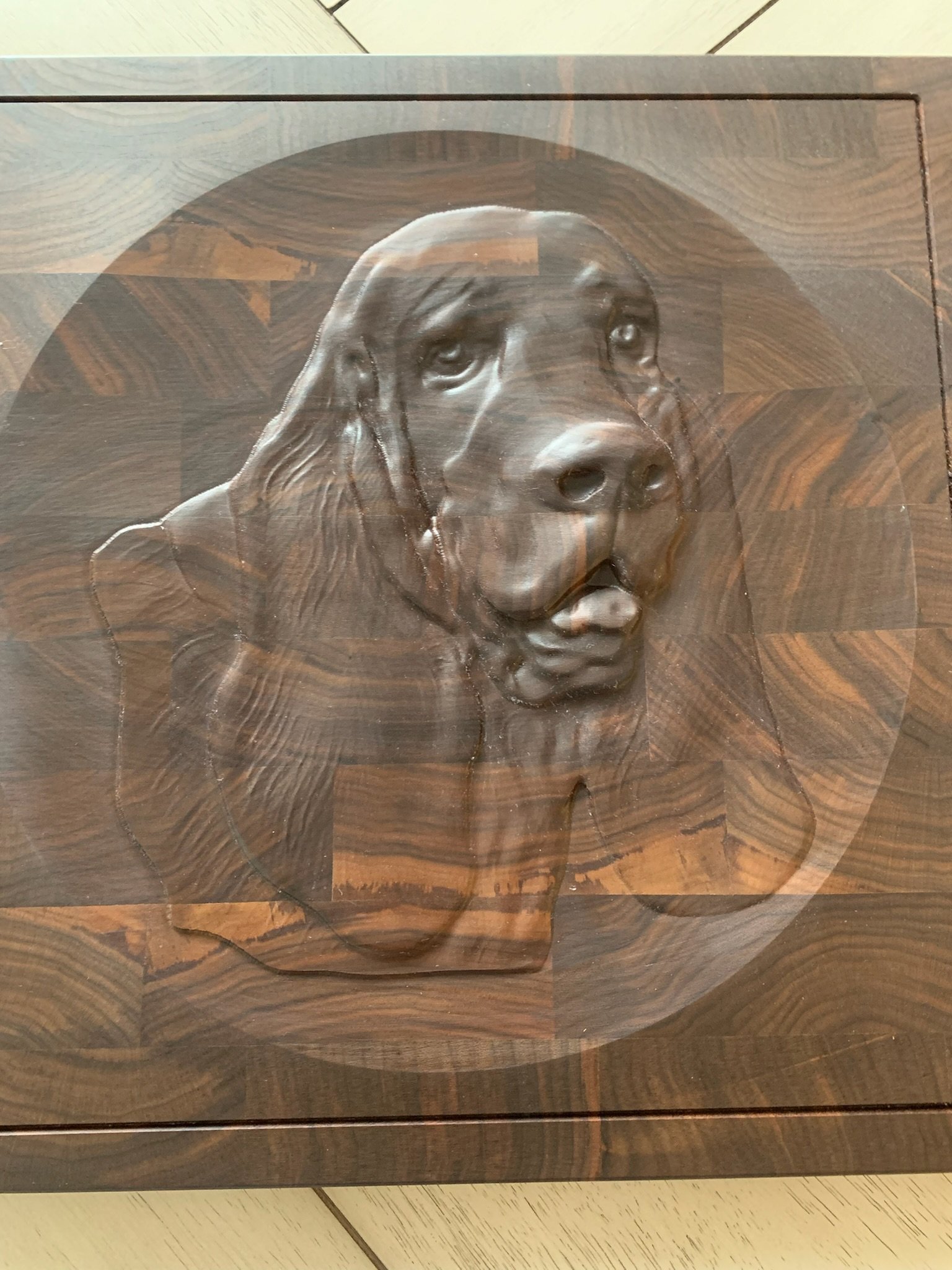 Wooden artwork of a dog's face carved into the surface.