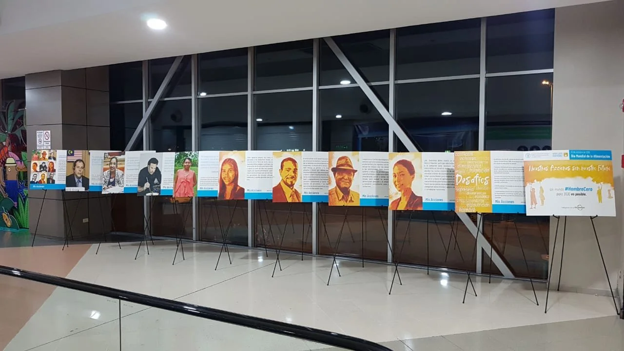Display of photographs and posters of various individuals, set up on stands inside a building, possibly for an exhibition or awareness campaign.