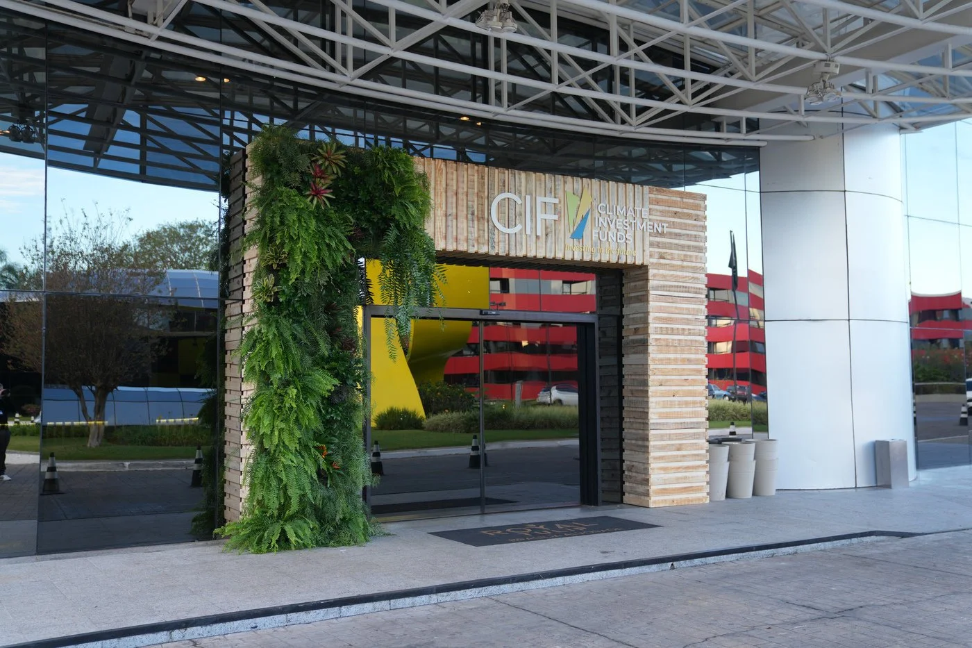 Entrance to Climate Investment Funds office building with green plants on the left side of the door, a large sign above the glass doors, and a futuristic architectural design.