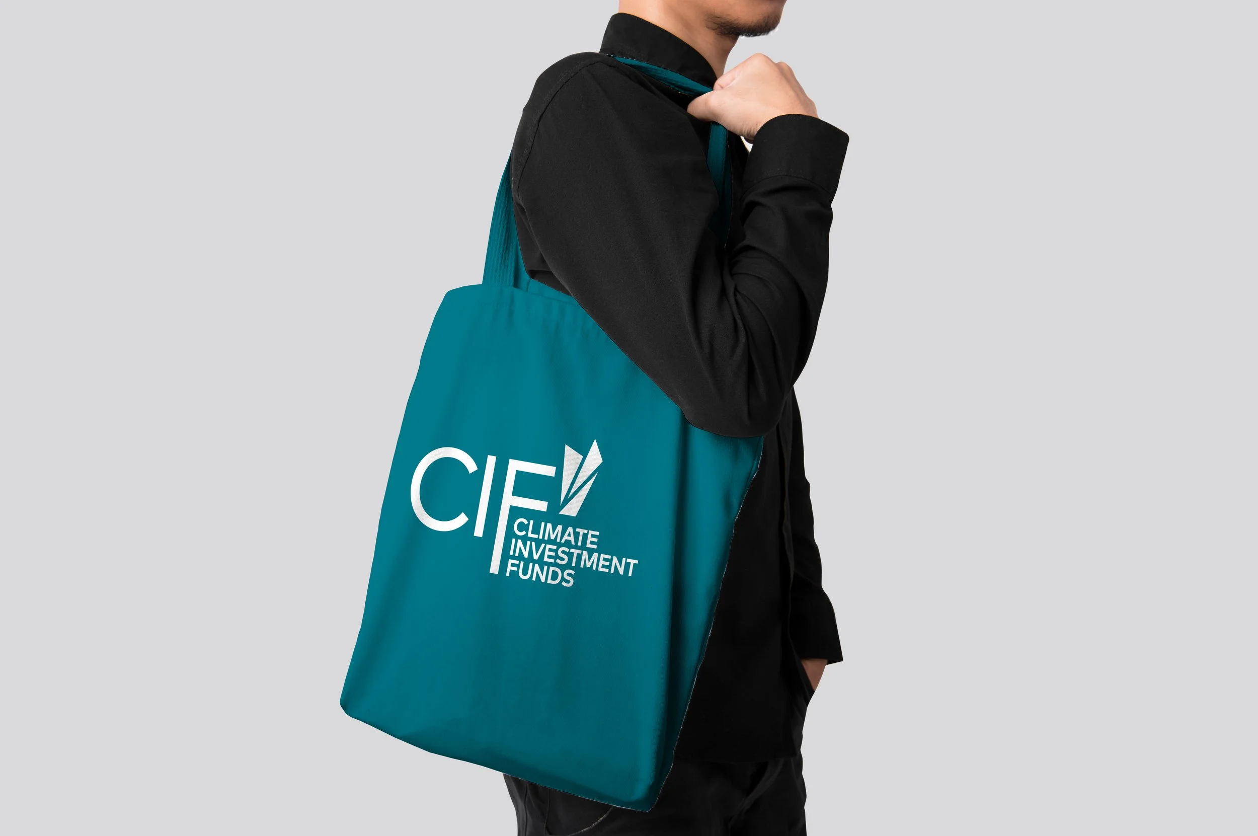 Person wearing a black jacket carrying a teal bag with the words "Climate Investment Funds" printed on it.