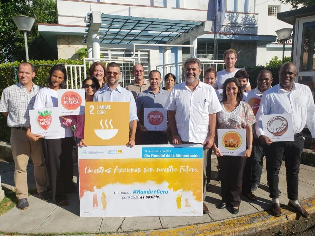 Group of people holding signs promoting World Food Day and the importance of zero hunger, standing outdoors.