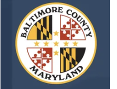 Seal of Baltimore County, Maryland with the words Baltimore County Maryland encircling shield divided into four quadrants with symbols and patterns.