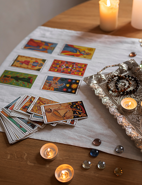 A table with tarot cards, candles, and decorative stones or crystals, used for tarot reading or spiritual practice.