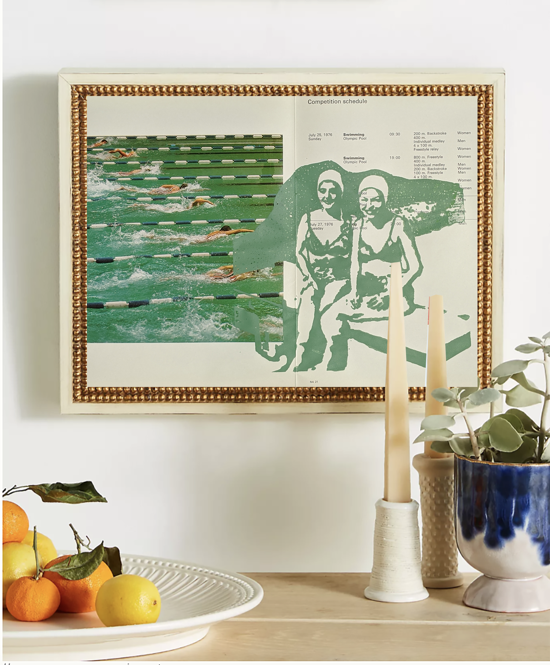 Decorative interior scene with a framed vintage swimming competition schedule, a vase with abstract blue and black art, and a potted plant with round leaves. A fruit bowl with oranges, lemons, and apples is in the foreground.