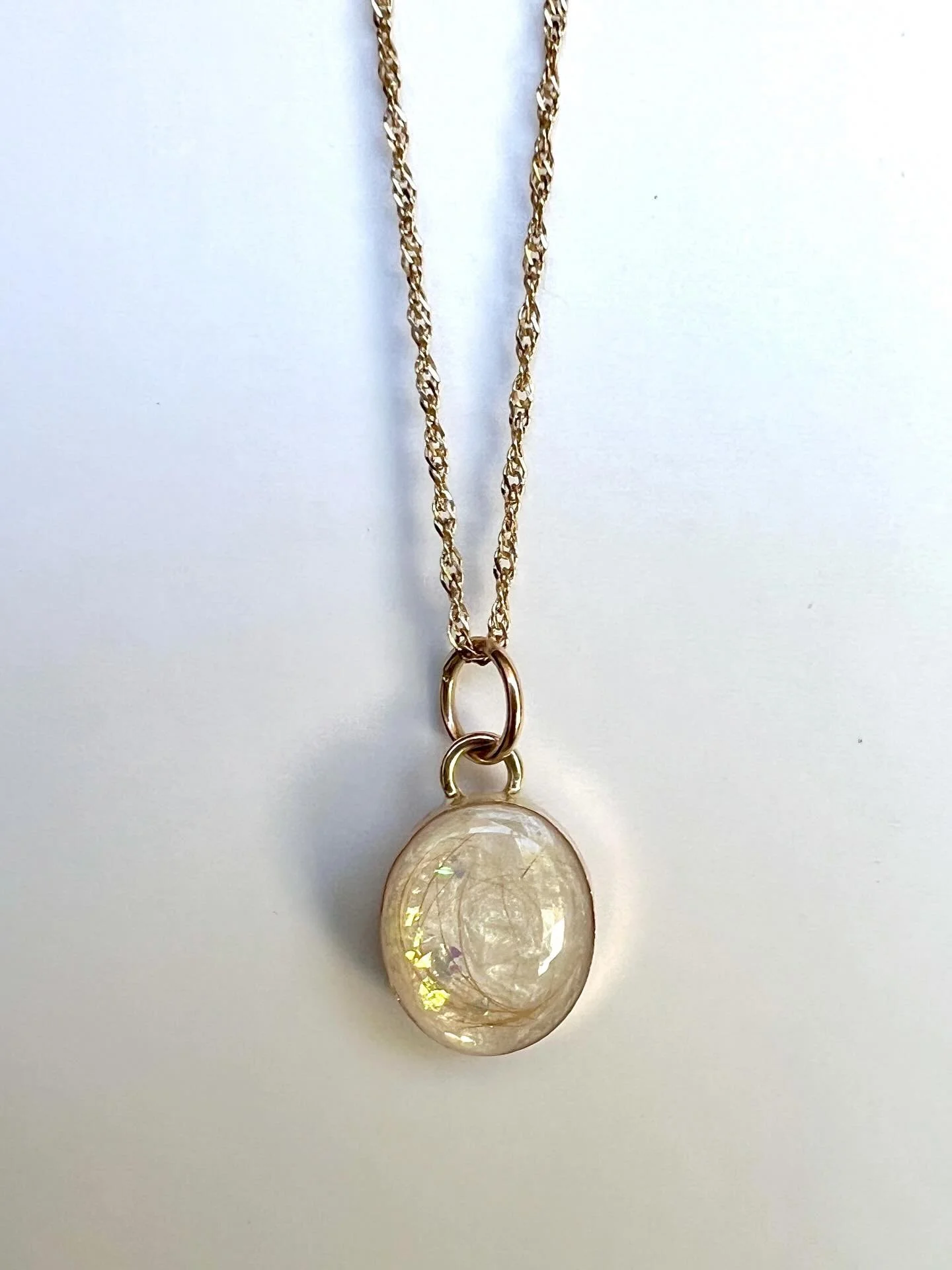 Necklace Charm preserving the hair of a sweet fur baby. Will always be with his mama. 

@mkadekodi 

Fur on top of a white background with opal dust. 
10x12 bezel cup pendent. 

#foreverloved #keepsakejewelry #petfurkeepsake #furbaby #southbay