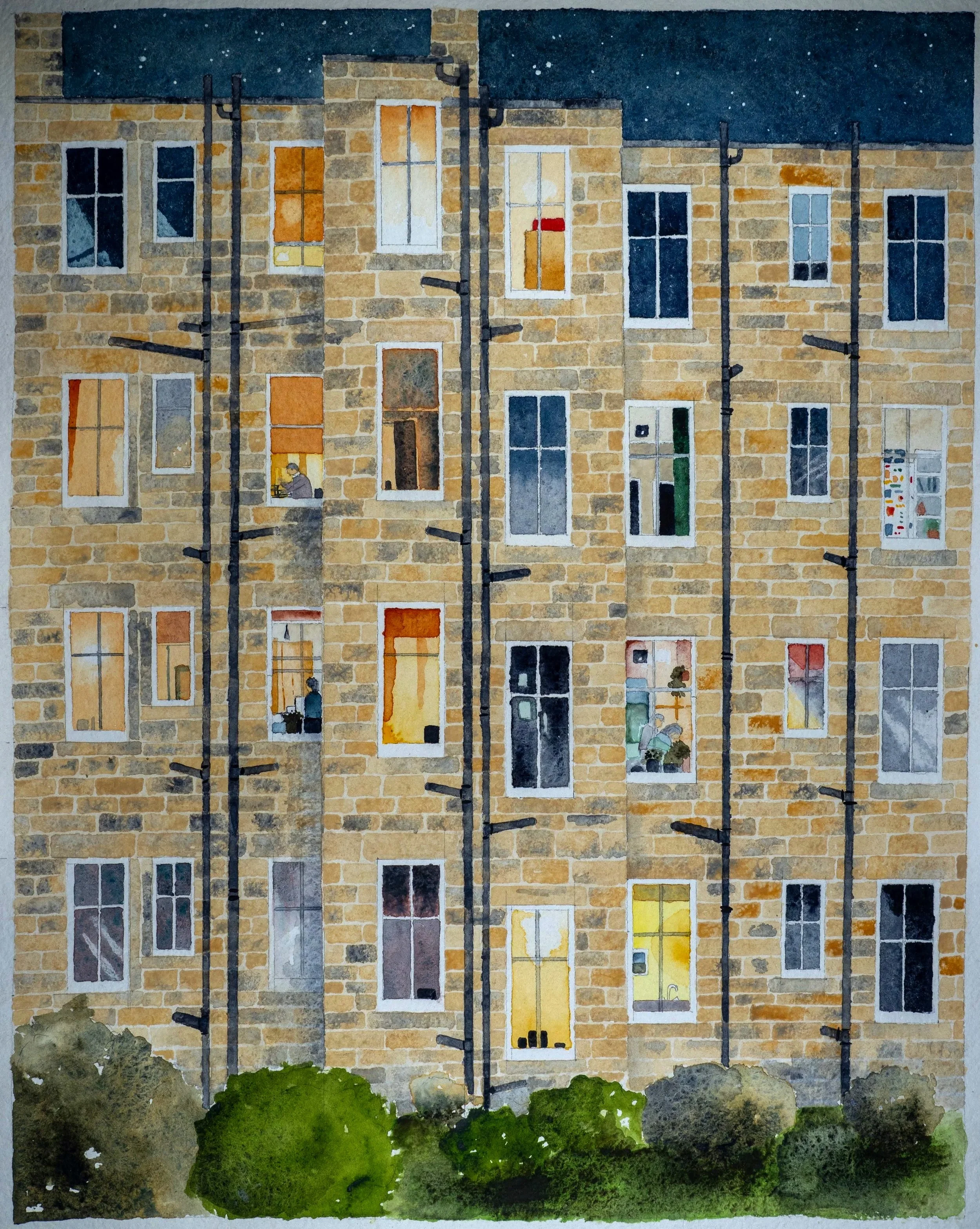 a grid of colourful windows in a tenement at night
