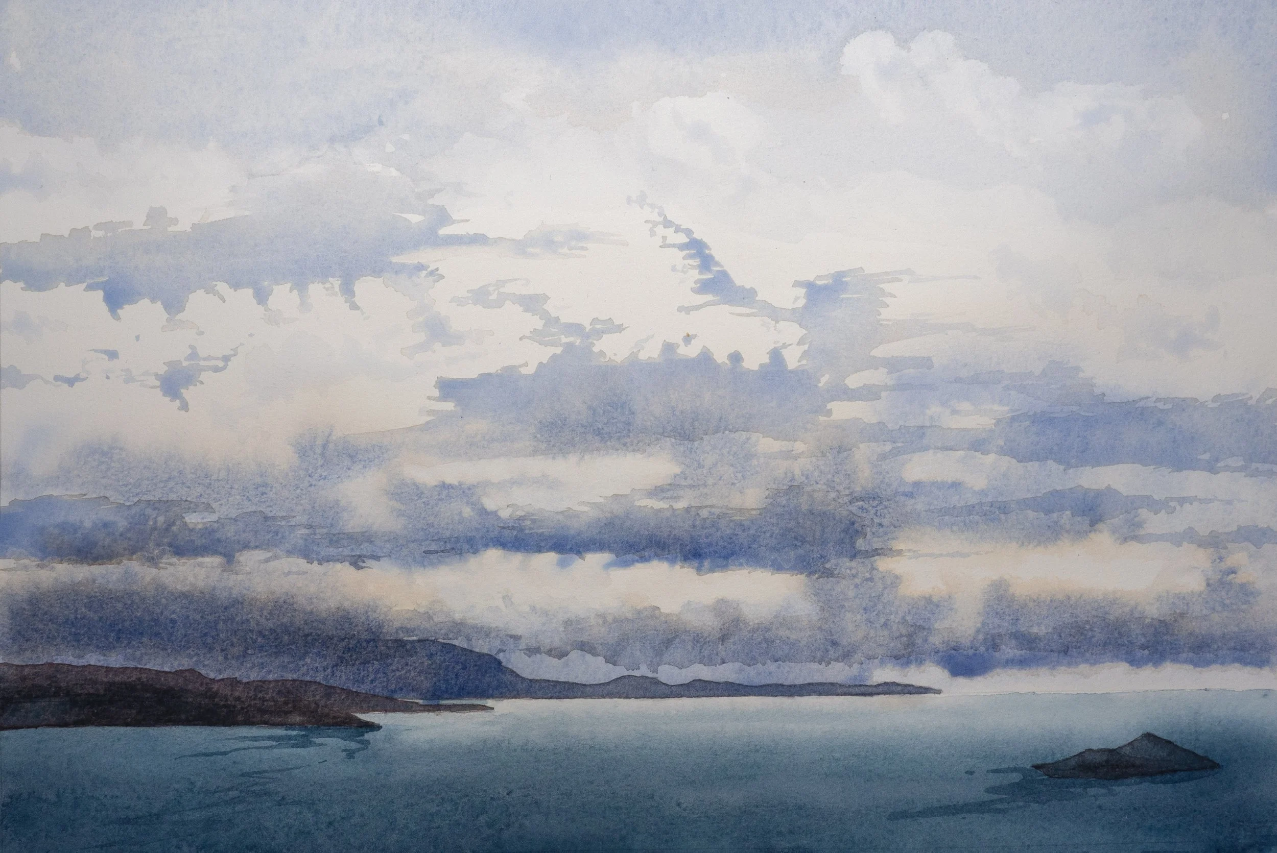 Islands and headlands in a dark blue sea with grey-blue clouds above