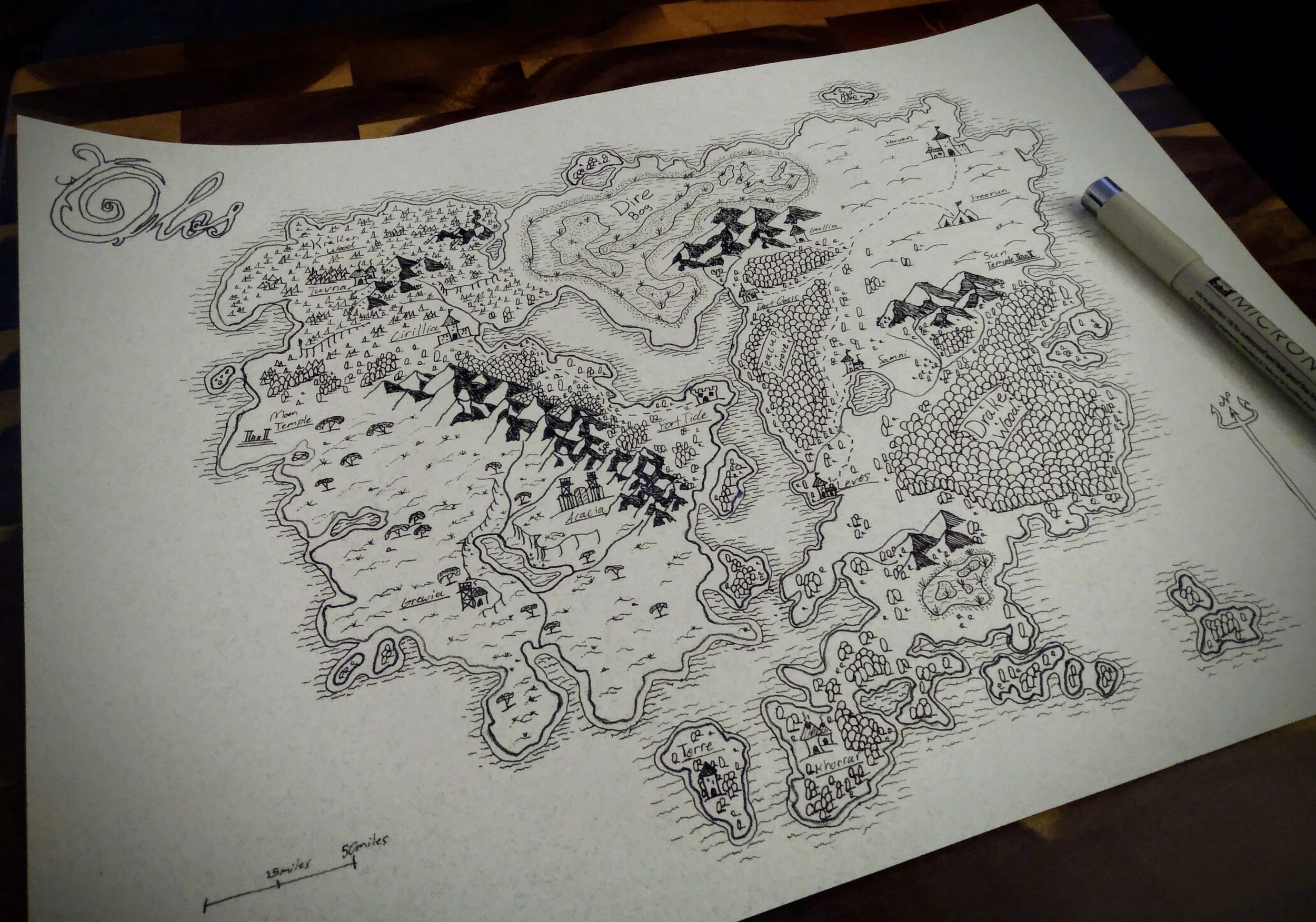 A detailed hand-drawn fantasy map on a piece of paper laid on a wooden surface, depicting various regions, landmarks, and place names, with a pen placed on the map.