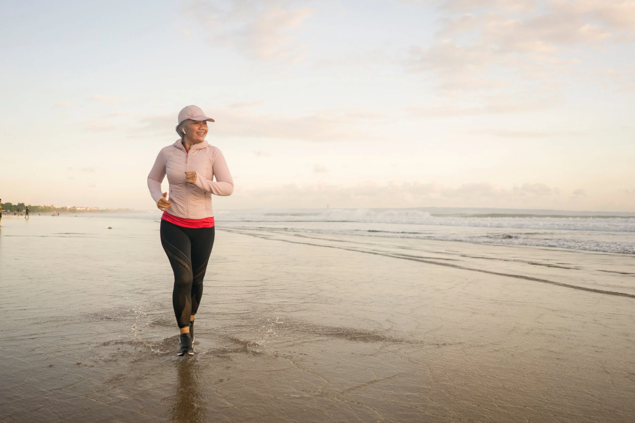 A woman jogging on the beach during sunrise or sunset.