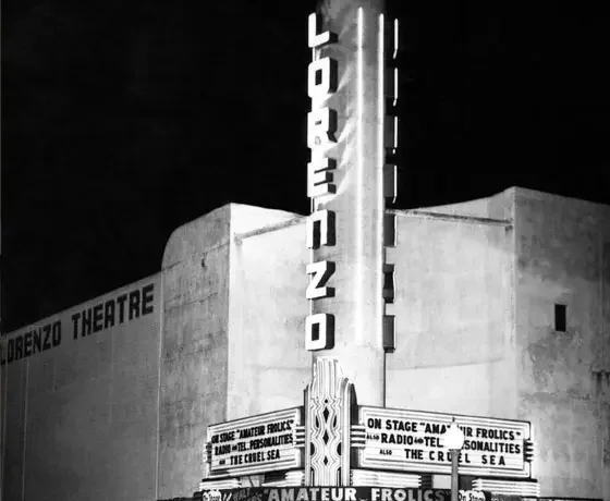 Black and white photo of the San Lorenzo Theatre with a vertical neon sign that reads 'Lorenzo.' Entrance marquee advertising a show titled 'Amateur Frolics' with additional details about the performance.