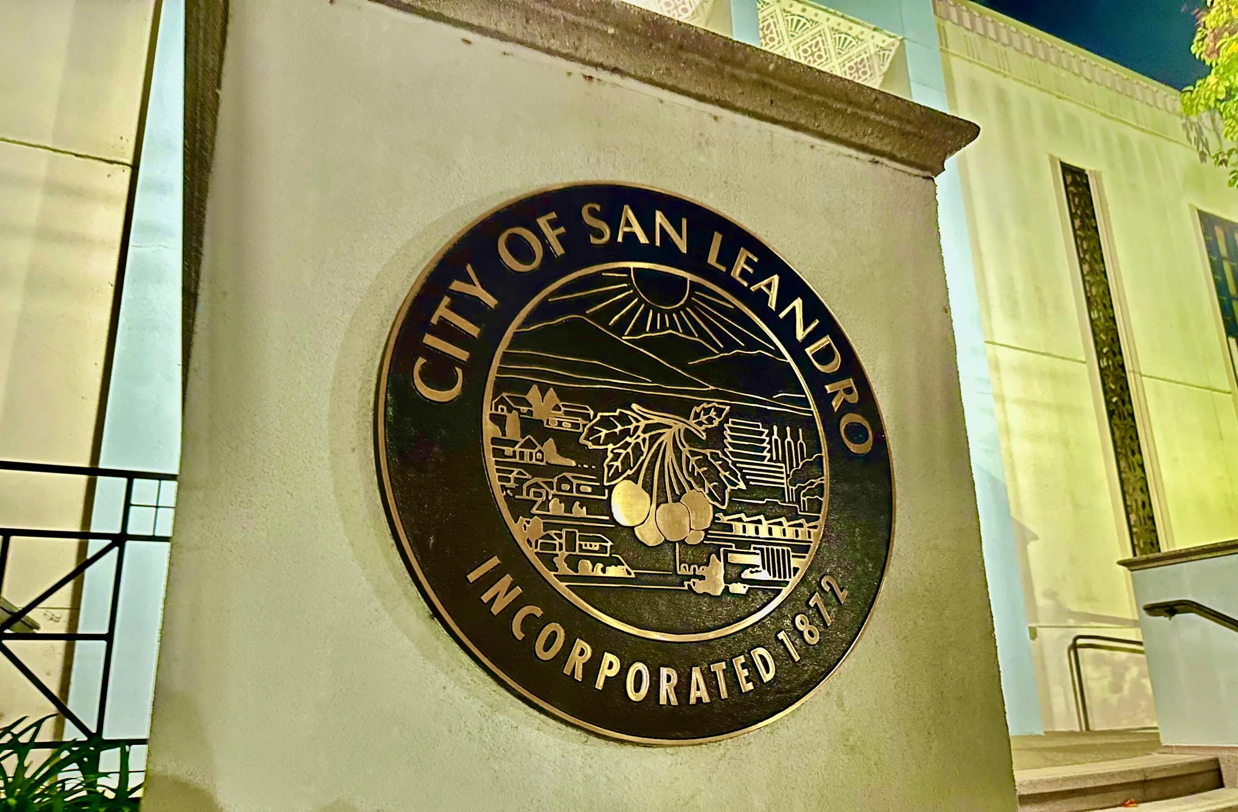 Seal of the City of San Leandro, showing a landscape with mountains, fields, and industrial buildings, along with the text 'City of San Leandro Incorporated 1872'.