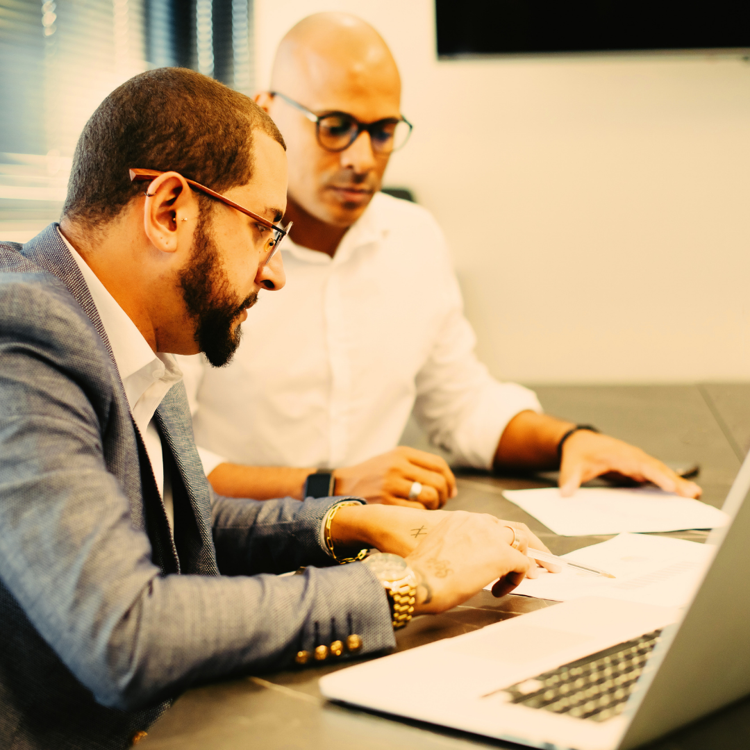 Two men working on a laptop in an office.