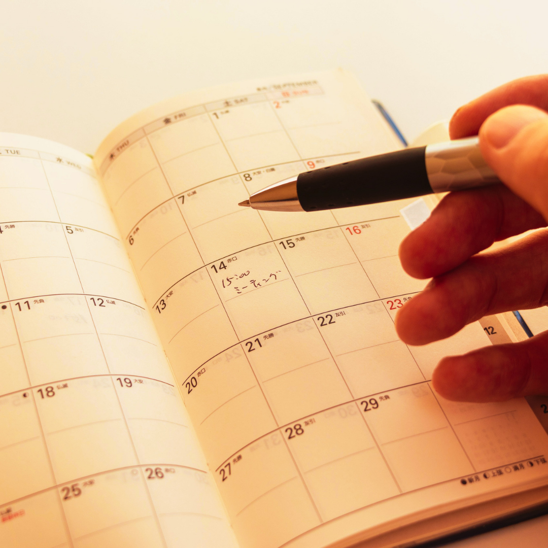 A hand writing on a monthly calendar with a pen. Inspection calendar