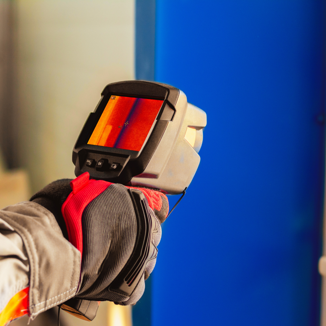 A person wearing gloves using a thermal imaging camera to scan a blue object.