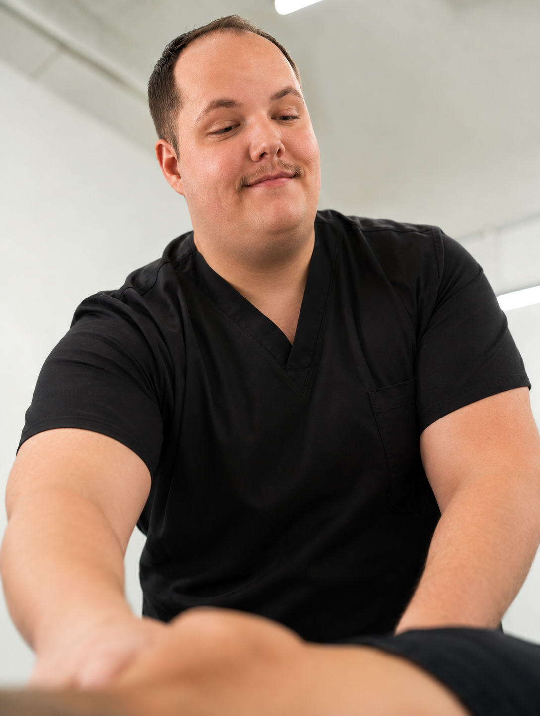 Un homme souriant, en uniforme noir, dans un environnement clinique.