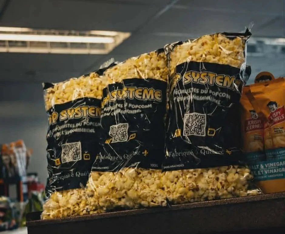 Trois sacs de popcorn emballés, placés sur une étagère dans un magasin.
