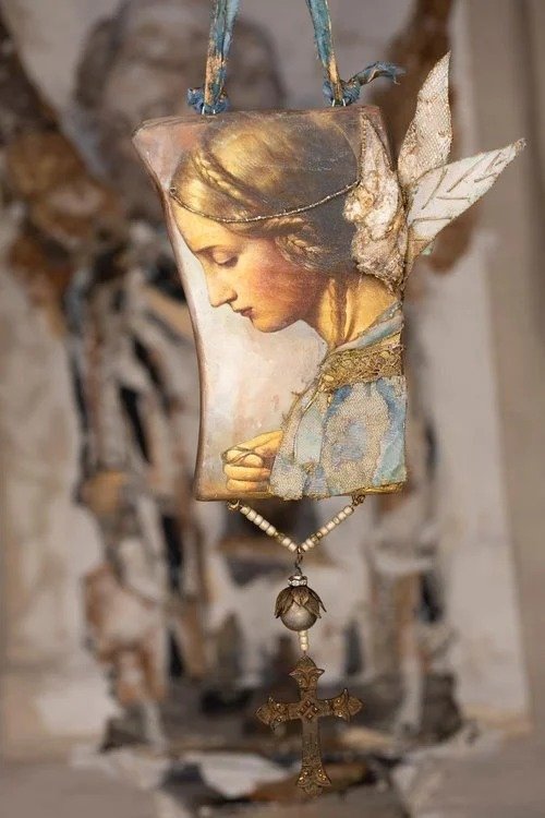 A mixed-media art piece featuring a portrait of a woman with wings, hanging with a chain and beaded necklace, set against a blurred background of a damaged wall.