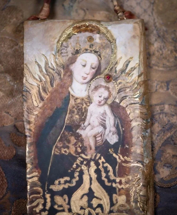 Religious icon of the Virgin Mary holding baby Jesus, adorned with gold accents and decorative elements.